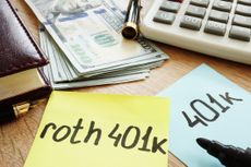 Post-it notes with "401(k) and "Roth 401(k)" written on them, with money and a calculator.