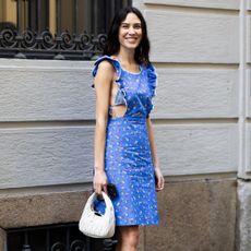 Alexa Chung wears a an apron dress with brown strappy heels and a white Miu Miu bag.