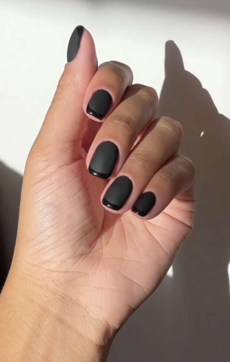 a person wearing square, black french manicure with a matte base