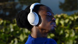 A man wearing a white pair of Bose QuietComfort Ultra Headphones.