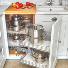 A kitchen cabinet storing stainless steel pots