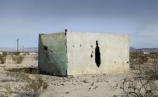 Large concrete block with a narrow oval aperture, in a desert setting