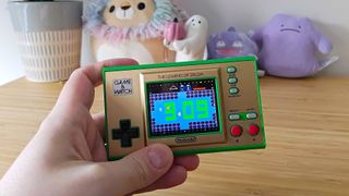 Hand holding Zelda: Game and Watch with clock mode displayed