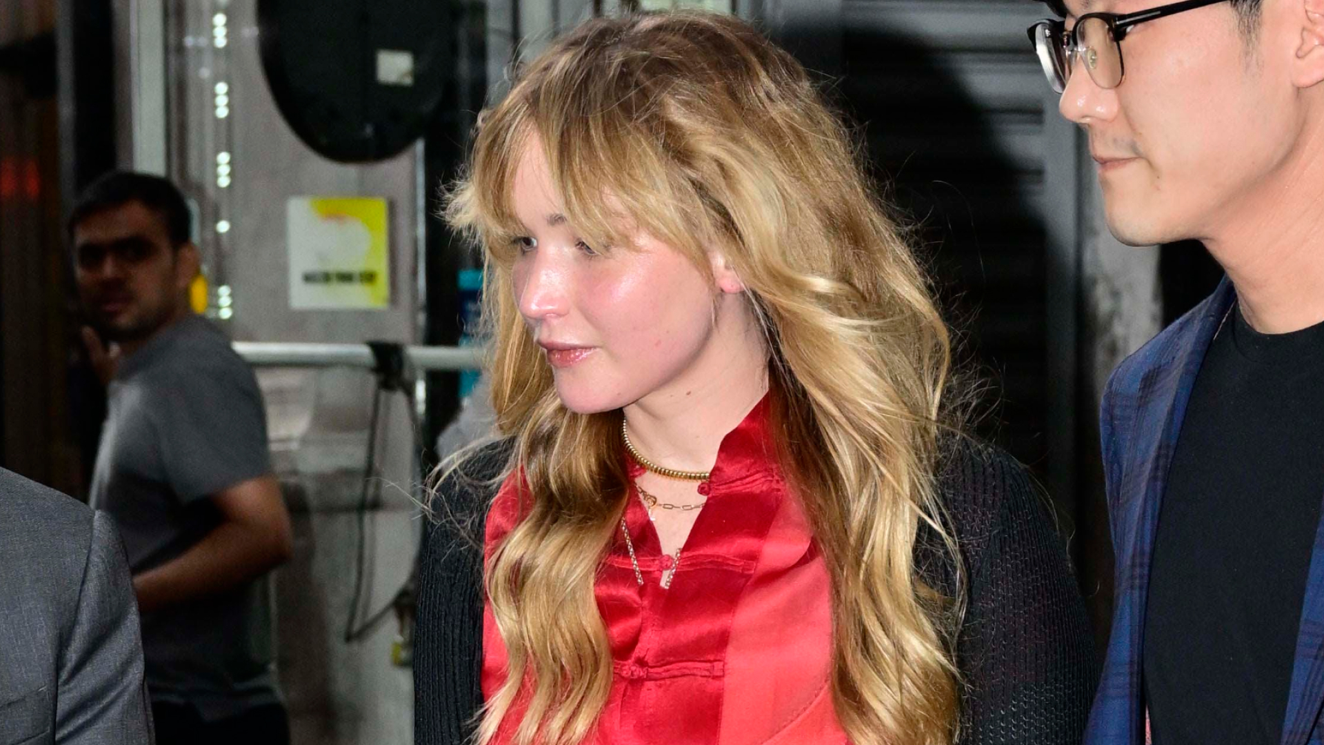 Jennifer Lawrence wears a black lace skirt with a red silk shirt and flat pumps