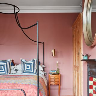 bedroom with metal framed four-poster bed patterned cushions and patchwork quilt on bed