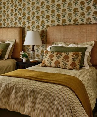 Yellow warm bedroom with printed wallpaper and matching pillows and twin beds with striped duvet