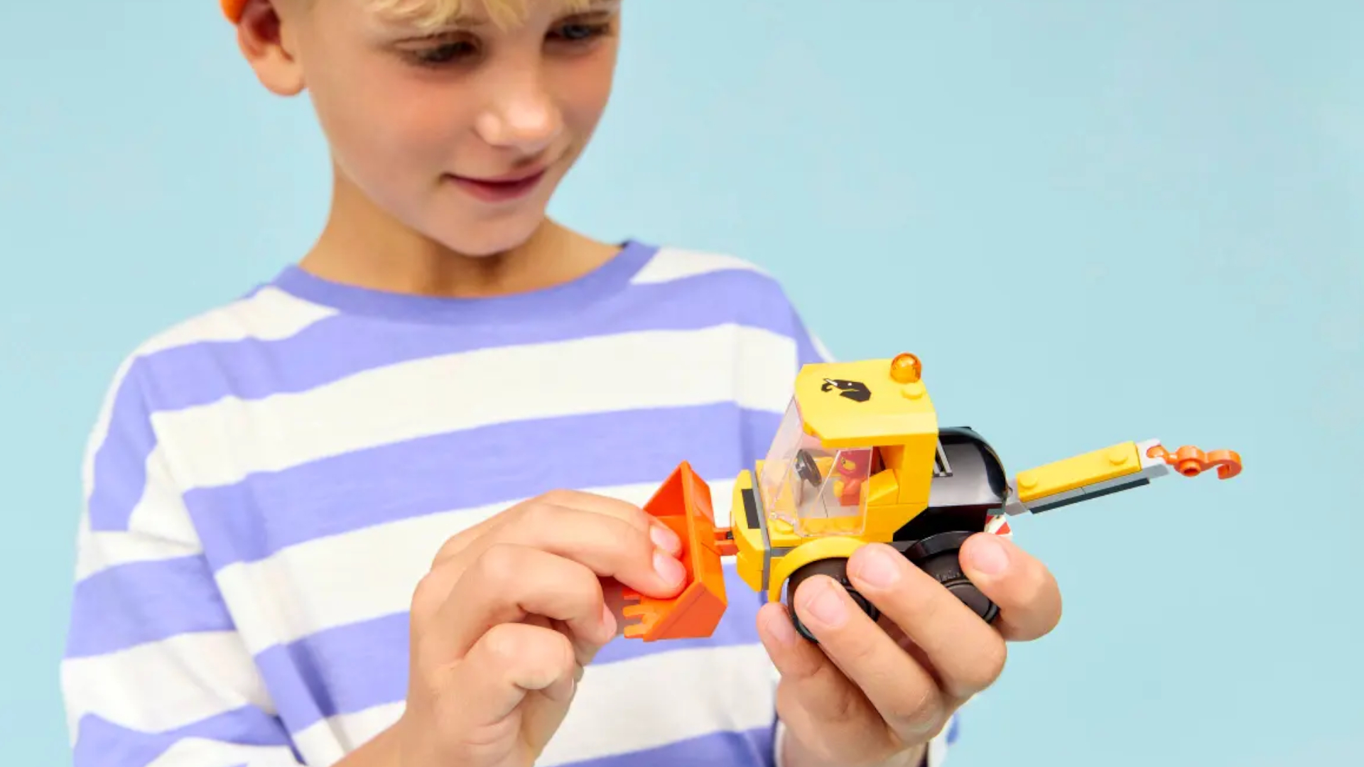 A child smiles while holding the Lego Rides - Construction Loader set