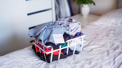 A wire basket full of clothes on a bed