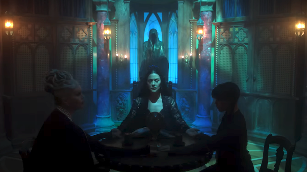 The Addams women holding hands while sitting on a table in creepy room in Wednesday Season 2 Part 2