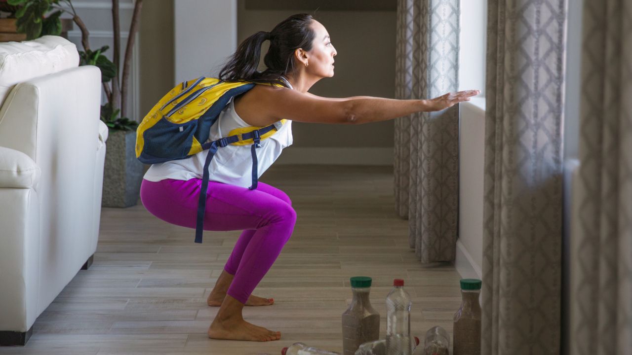 A woman performing squats while wearing a rucksack