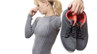 A lady in sportswear is repulsed by her stinky trainers