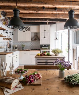 white kitchen with beamed ceiling and rustic wooden farmhouse table