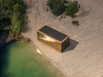 ood golden house cabin seen from above by the shores of a lake