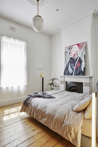 A bed in a bedroom and painting on wall.