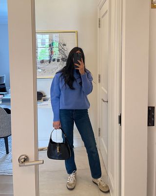 A woman taking a mirror selfie and holding a Gucci Jackie bag.