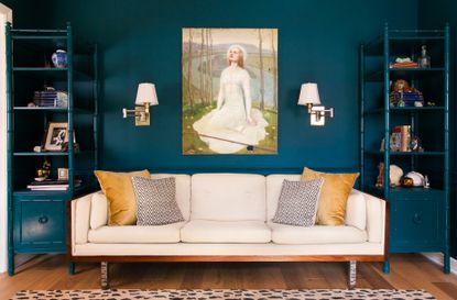 A living room with teal walls, and a cream sofa