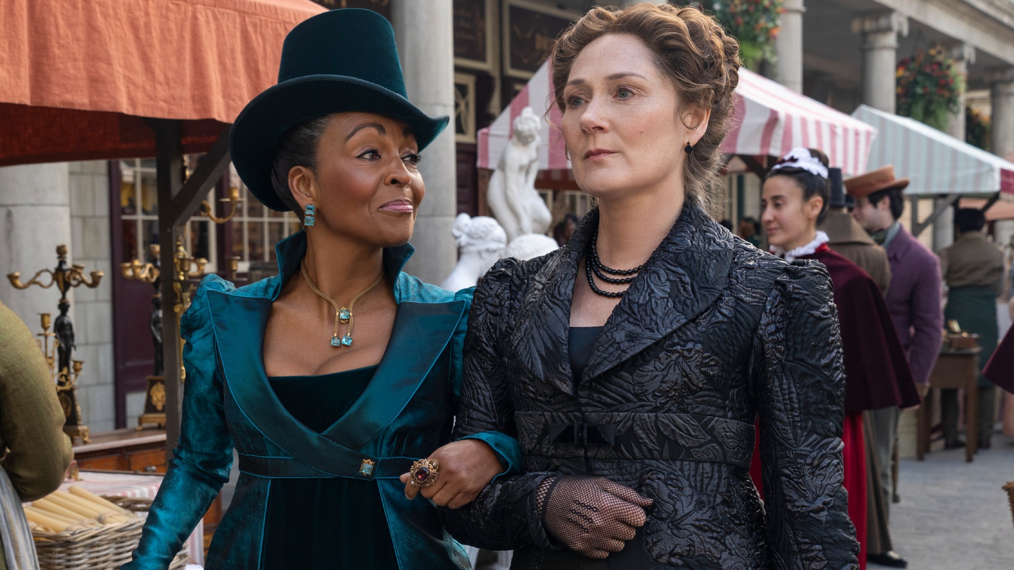 (L to R) Adjoa Andoh as Lady Danbury, Ruth Gemmell as Lady Violet Bridgerton walking arm in arm in Bridgerton.