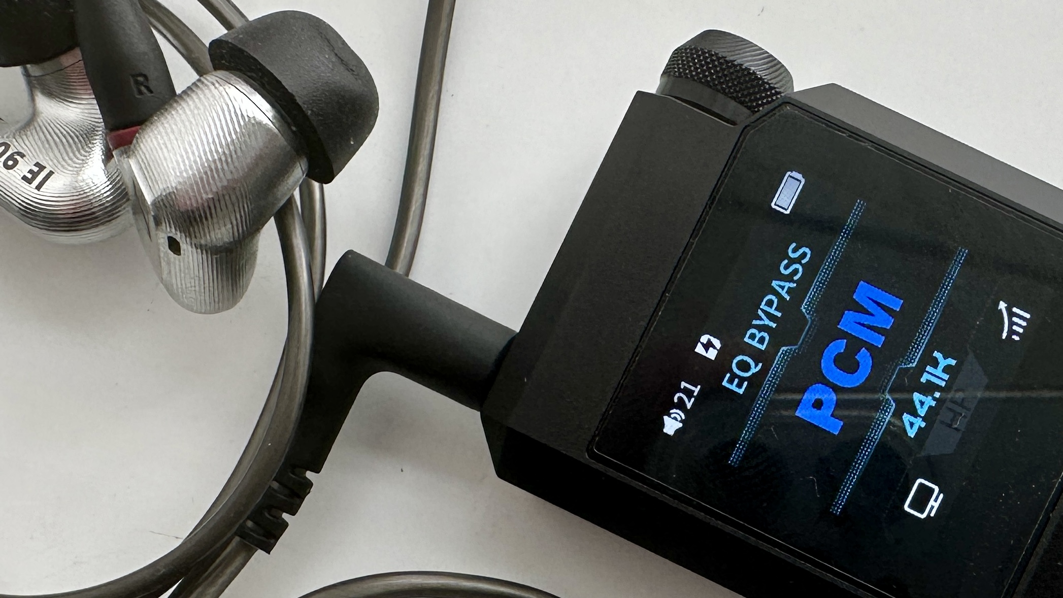 FiiO's BTR17 DAC/amp in black, on a gray table, showing PCM resolution in yellow font