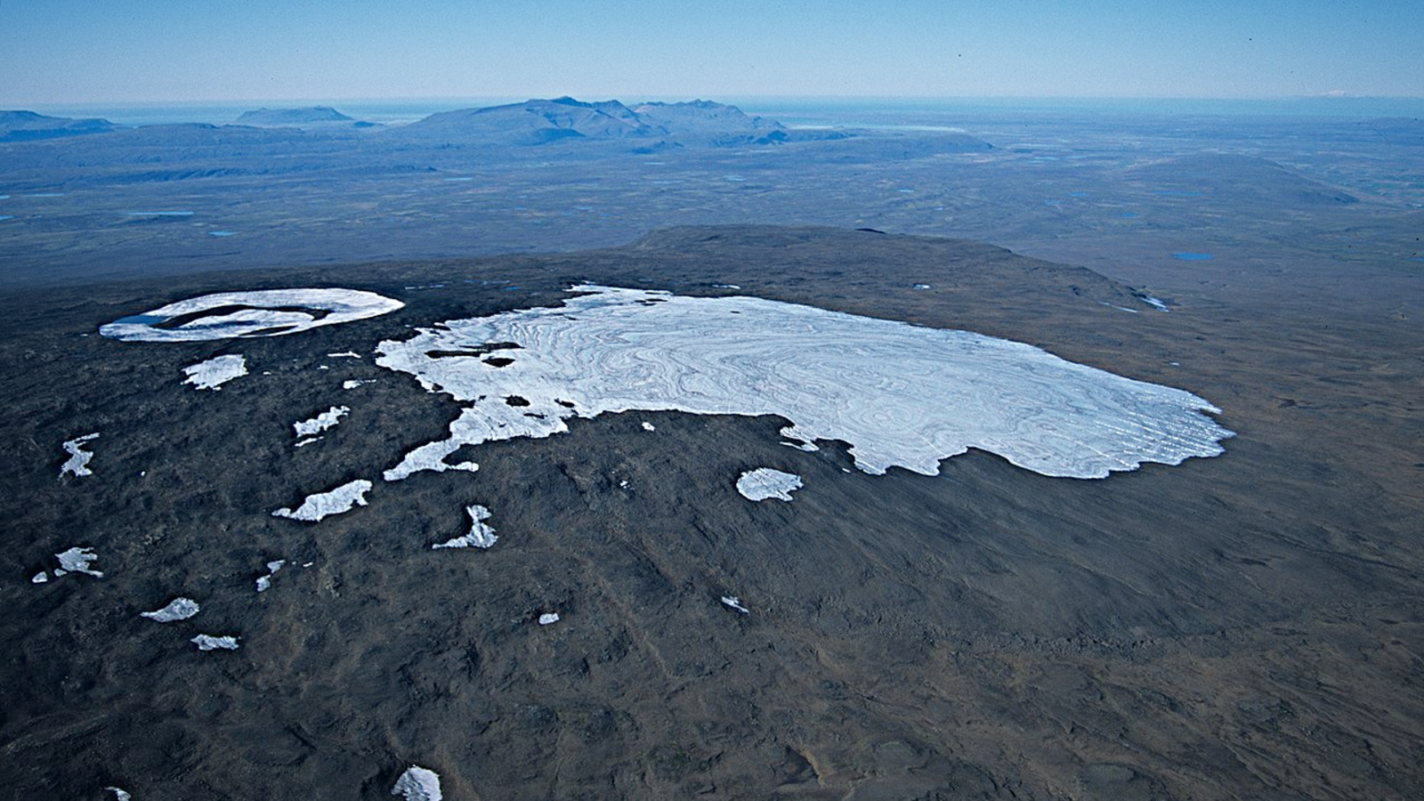 An aerial photo showing a glacier at the summit of a mountain