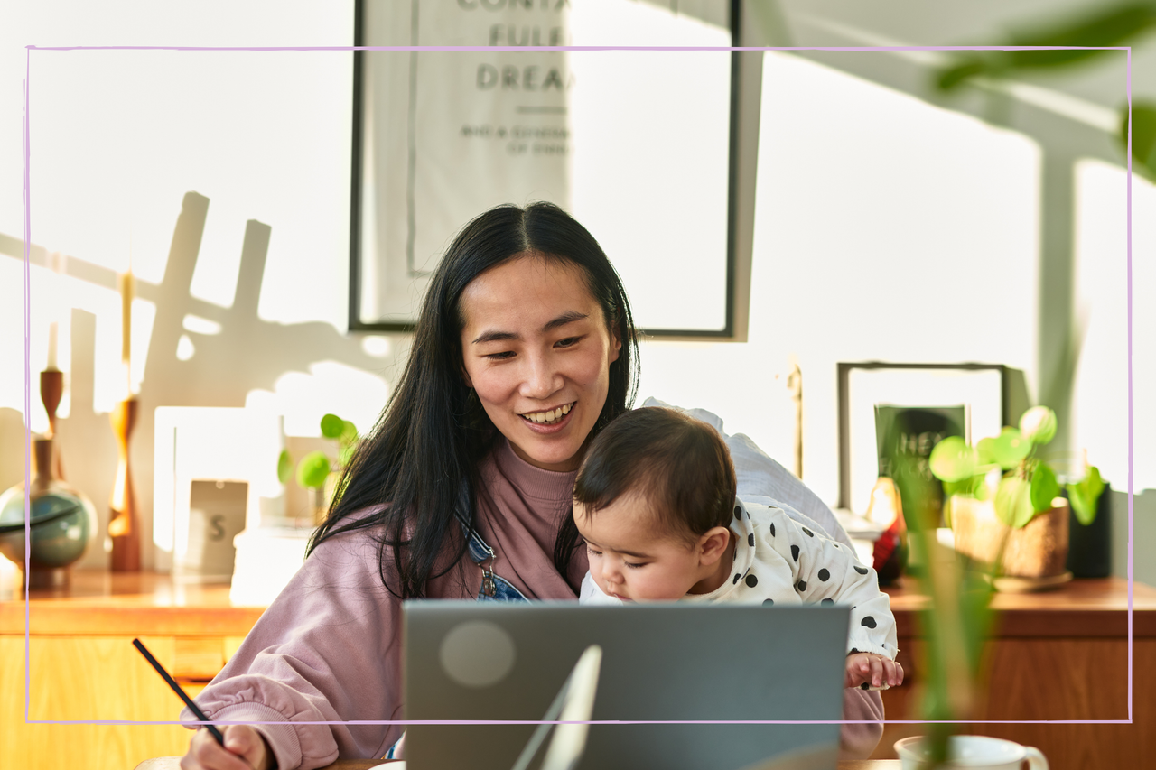 Businesswoman working at home with baby daughter on lap in front of laptop