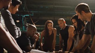 The entire Fast Five crew standing around a table