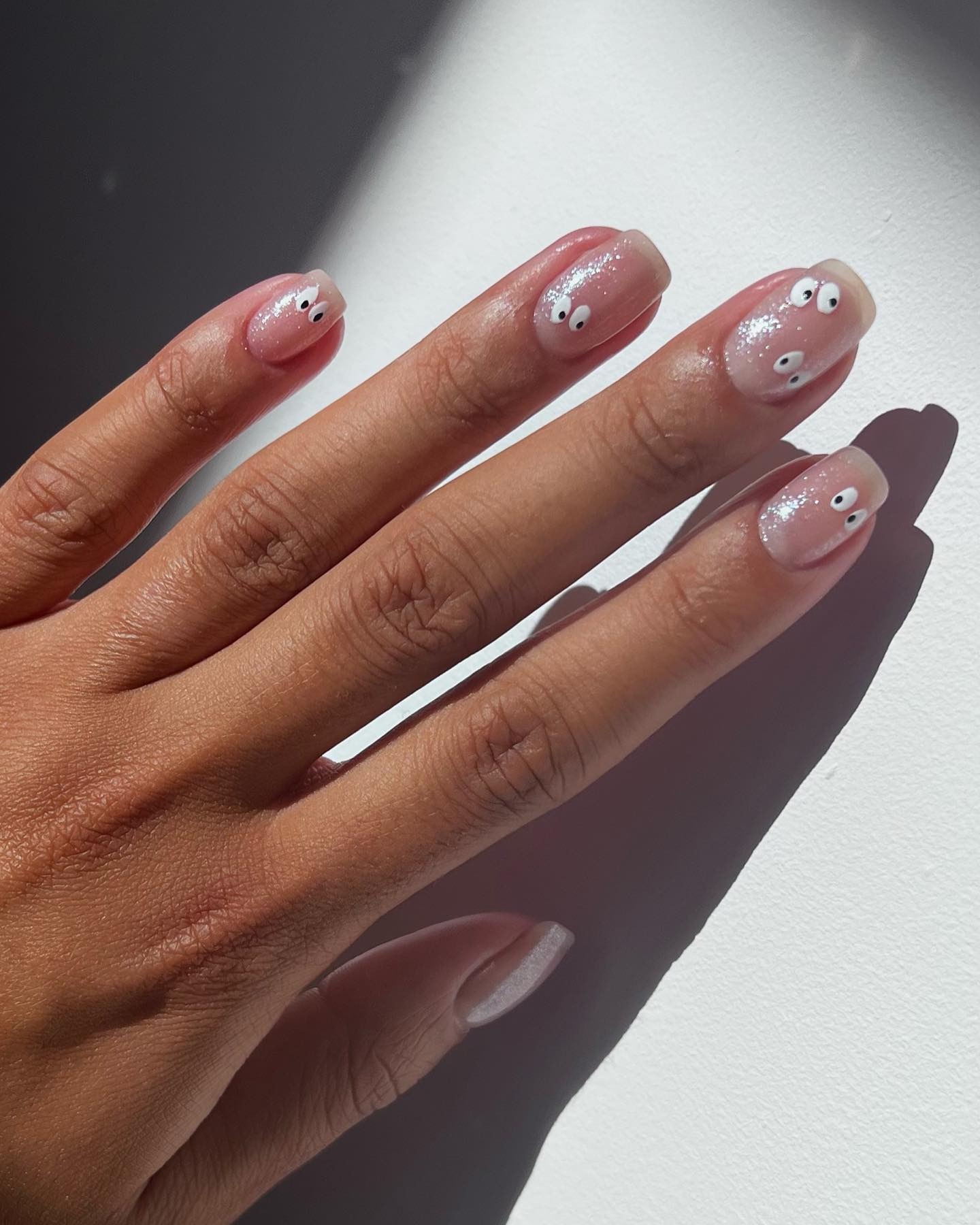 Sheer shimmery nails with cartoon eye nail art