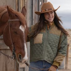 minka kelly wearing a barn jacket and cowboy hat standing next to a horse in ransom canyon