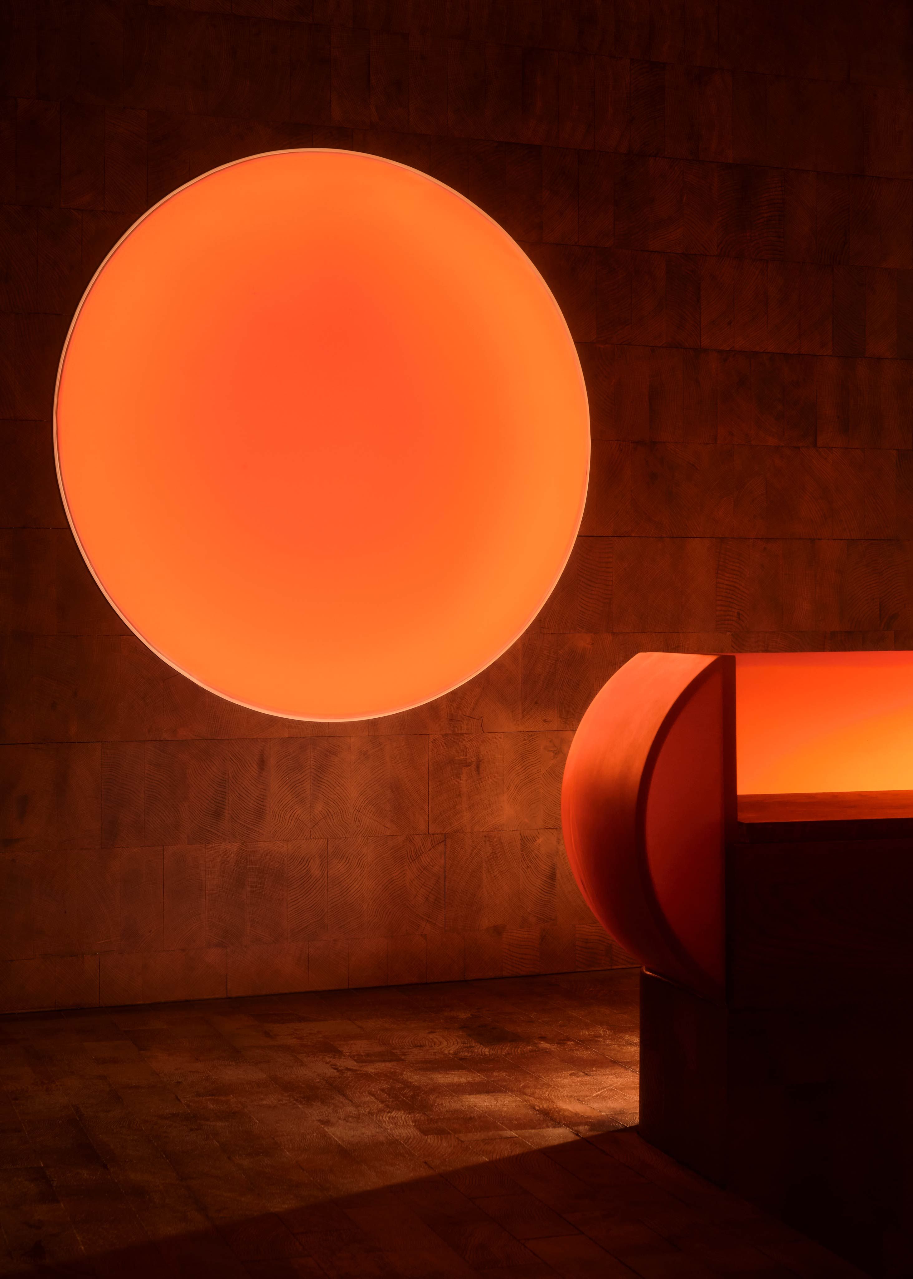 The atmospherically lit nooks of a listening bar, featuring spherical, orange-tinted light installations, wood and chrome surfaces, and plush, earthy textiles.