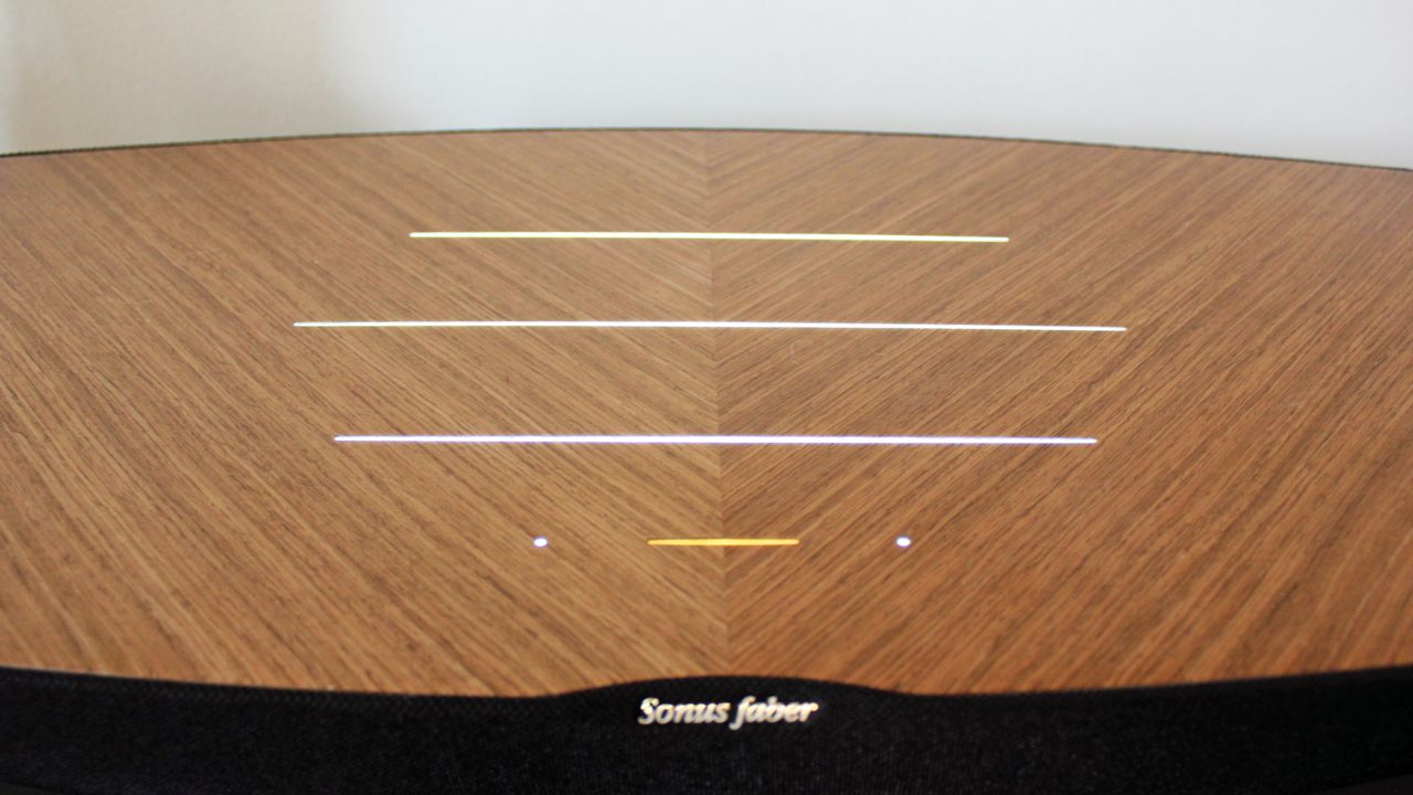 A view of the top of the Sonus Faber Omnia, showing its wooden finish and some horizontal lines that act as design flourishes and on-device controls and indicators