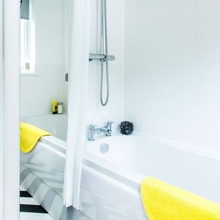 bathroom with bathtub yellow towel and full length mirror