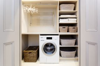 Utility room storage solutions showing a close up of a washing machine and radiator hidden behind large cabinet doors