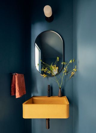 a blue powder room with a yellow basin