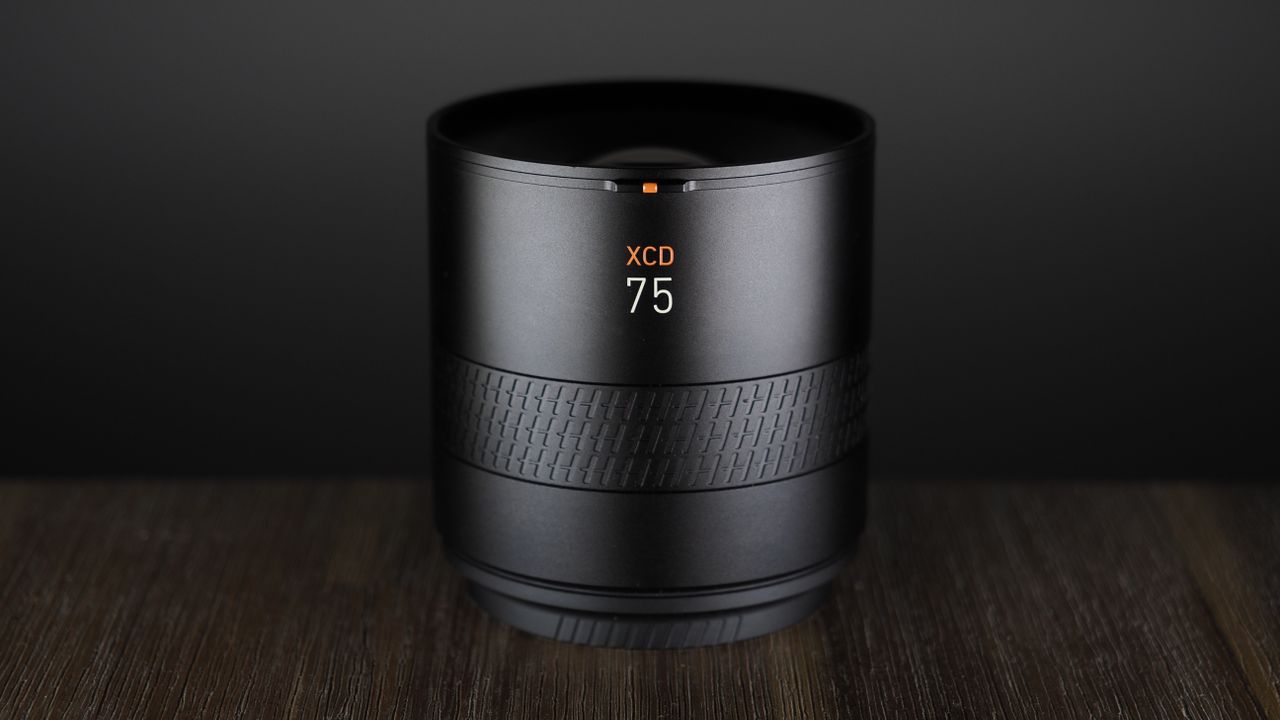 Hasselblad XCD 75P lens, on a wooden surface, against a dark background
