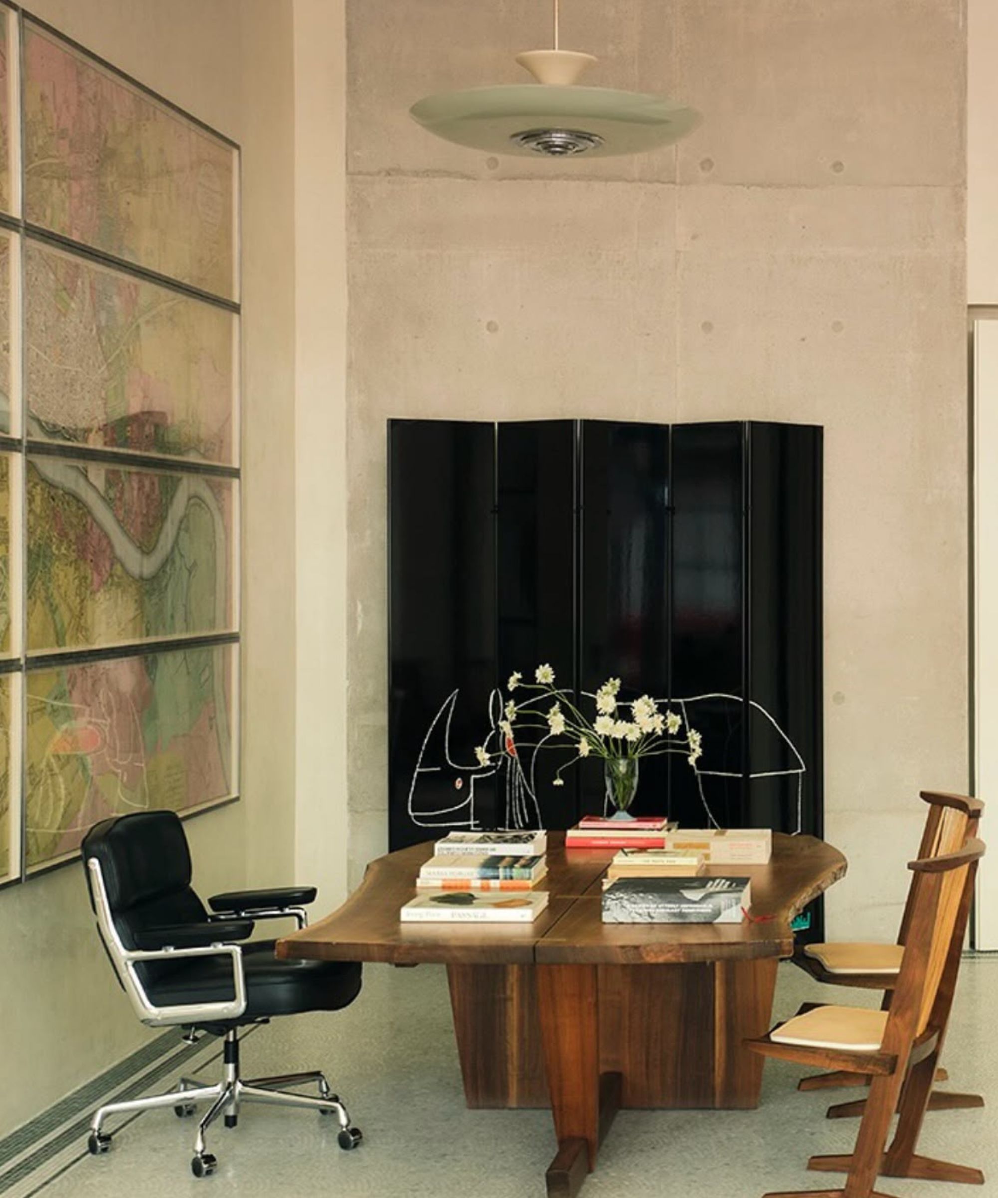 Large modern study with large wooden table and chairs, black and metal desk chair, large map artwork behind desk, black screen to left