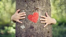 Benefits of nature on health: woman hugging tree with heart