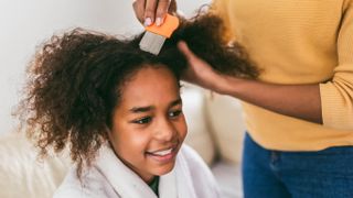 Someone removing head lice from a young girl's hair