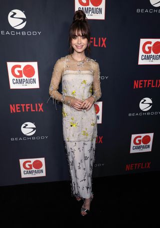 Lily Collins attends the 15th Annual GO Gala hosted by Lily Collins at City Market Social House on October 08, 2022 in Los Angeles, California wearing a sheer embellished Prada look and metallic Prada heeled sandals