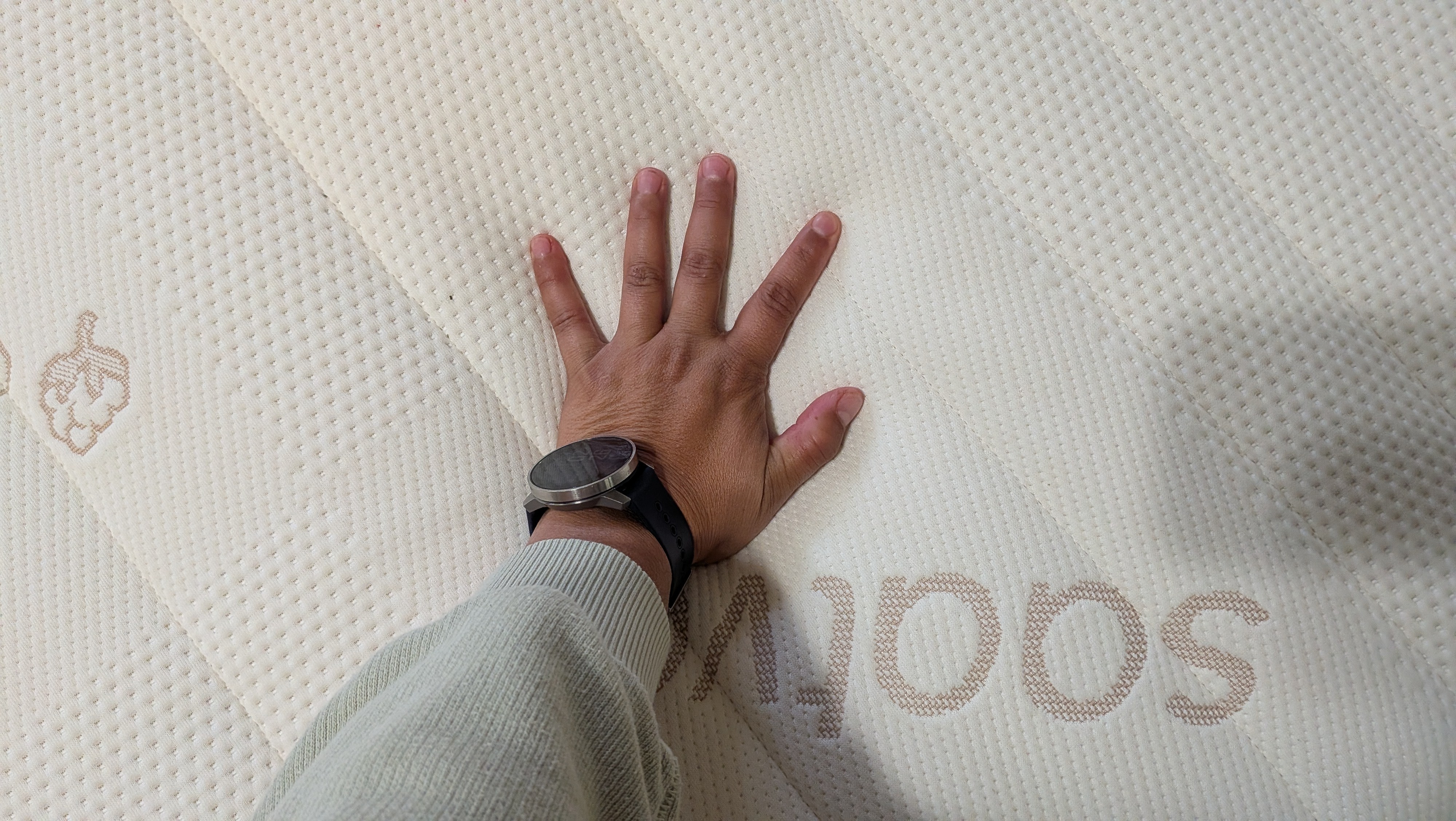A Tom's Guide mattress tester places her palm on the surface of the Saatva Zenhaven Latex mattress.
