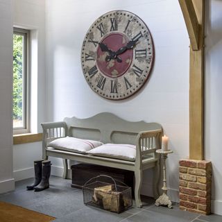 white hall with wall clock and grey bench