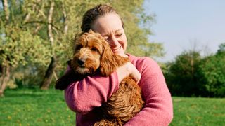 Lady cuddling dog as an example of how to be the best dog owner