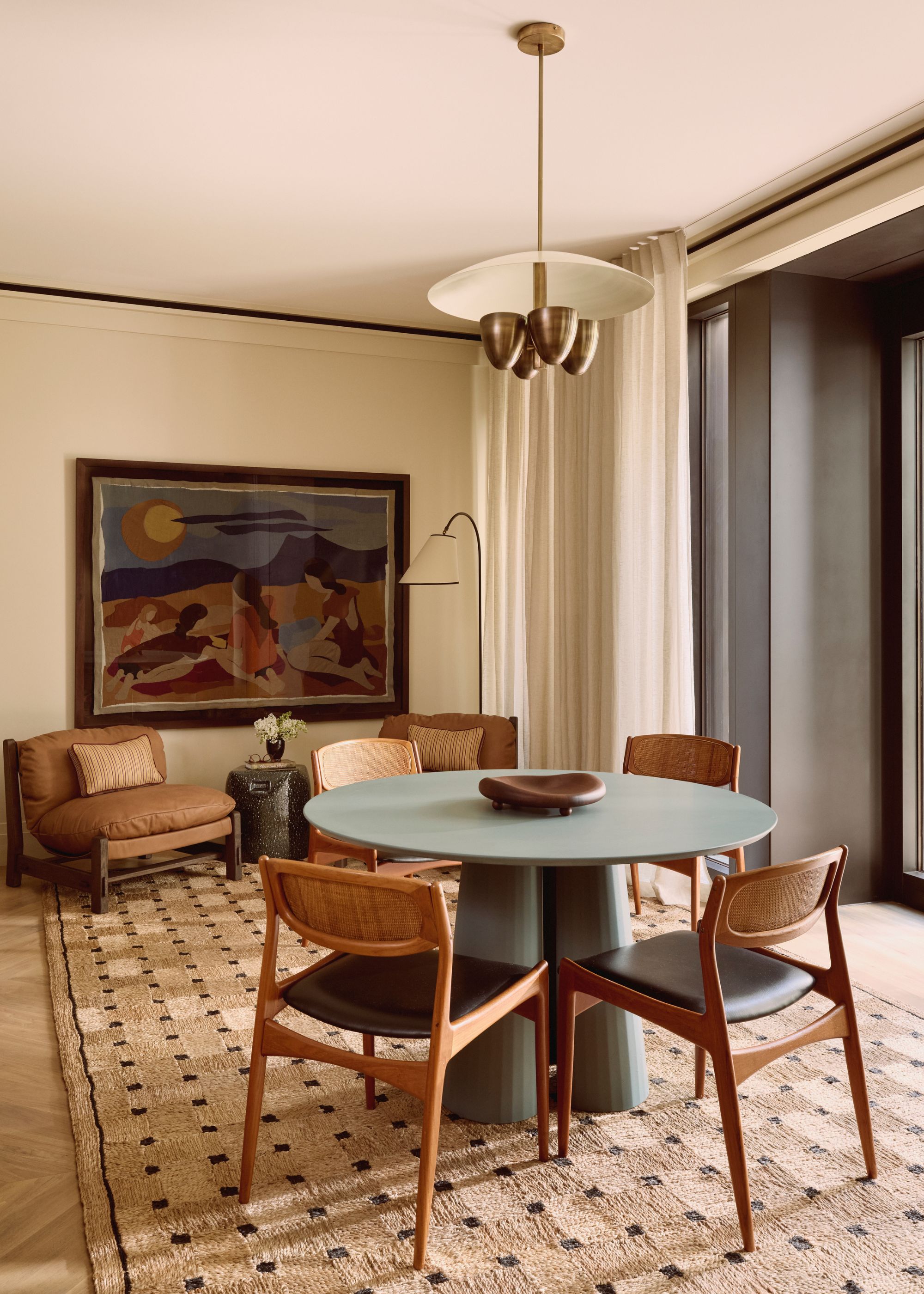 A dining room with floor carpeting, a round seating and a light above