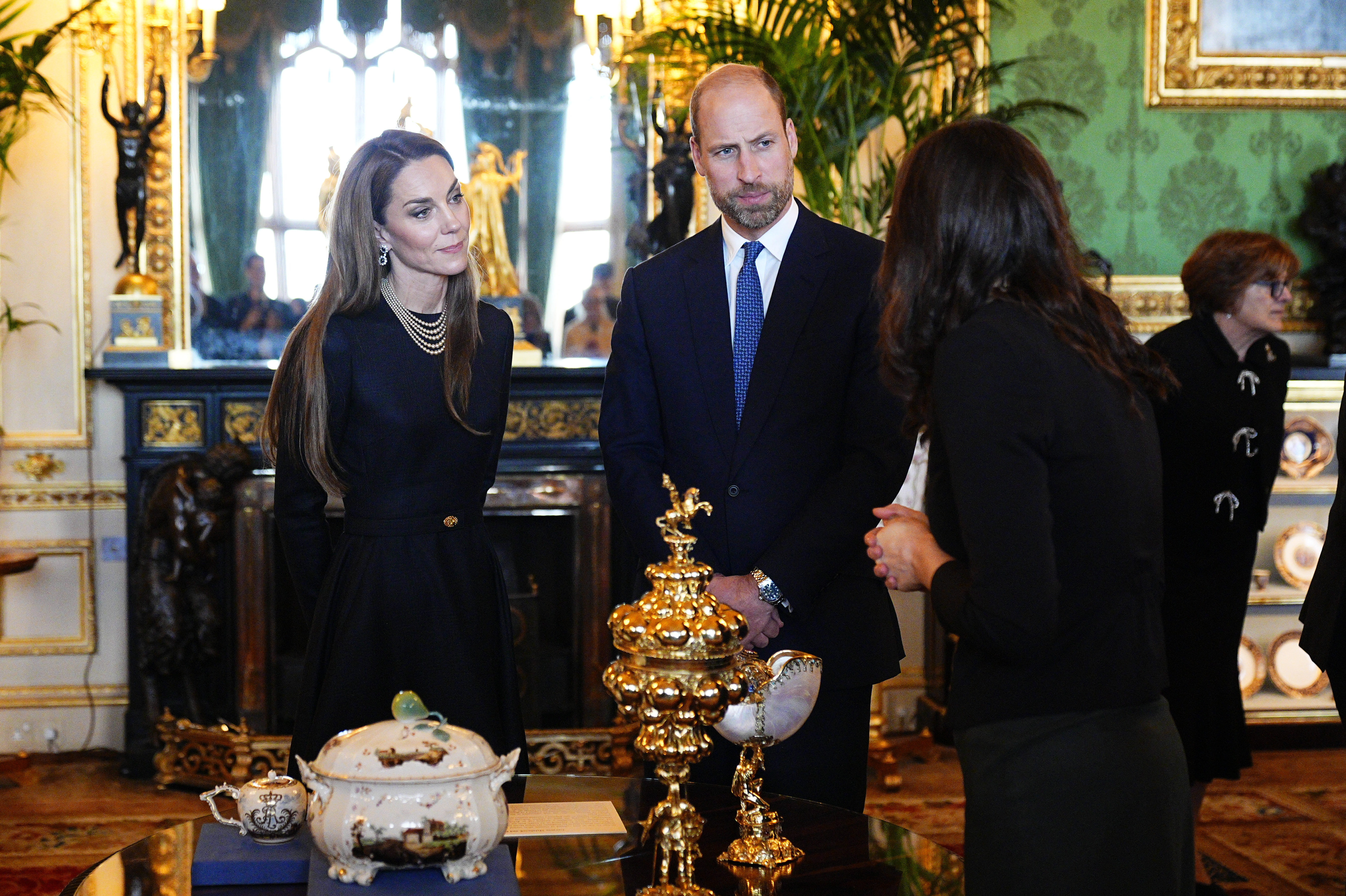 Princess Kate and Prince William standing in front of a table and talking to a woman at Windsor Castle