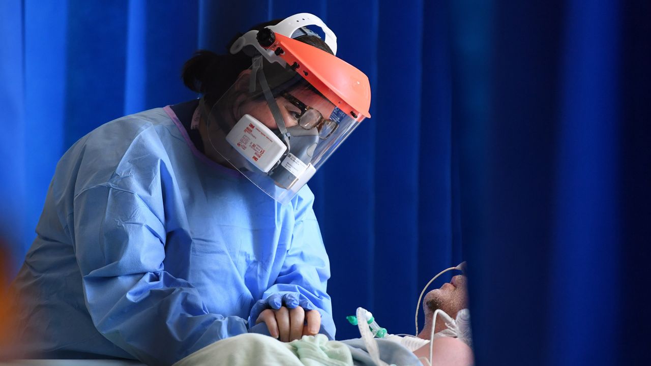 A Covid patient is treated by a member of NHS staff wearing PPE.