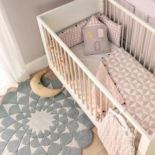 room with wooden cot bumper hand tufted lotus rug and moon cushion