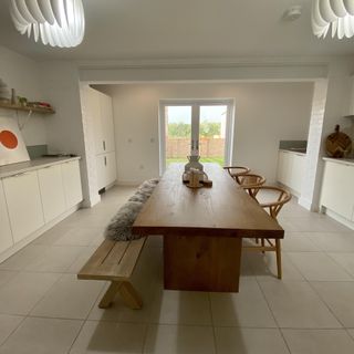 large wood dining table with wood chairs and bench in white kitchen