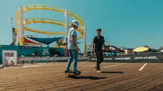 Person riding a Onewheel electric skateboard in front of an amusement park