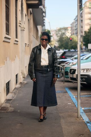 Nikki Ogunnaike in a long denim skirt, white button-down shirt, and black leather jacket.