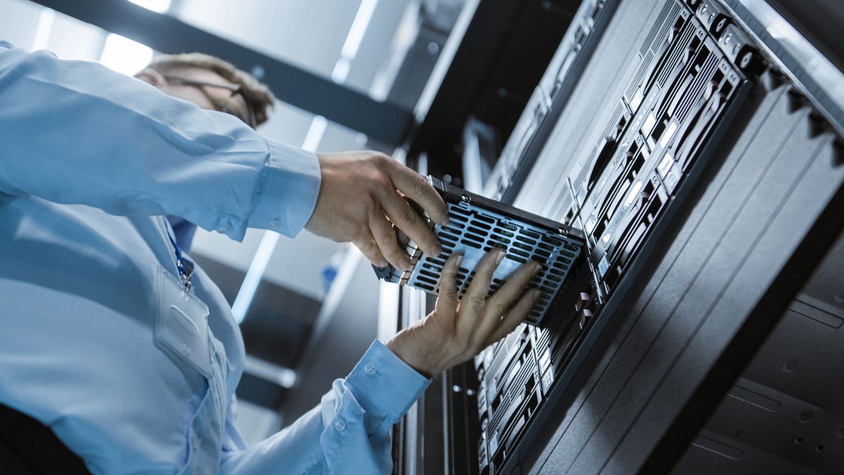 A person putting a storage device into a rack in a data centre