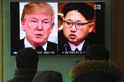People watch a television news report showing pictures of President Trump and North Korean leader Kim Jong Un at a railway station in Seoul