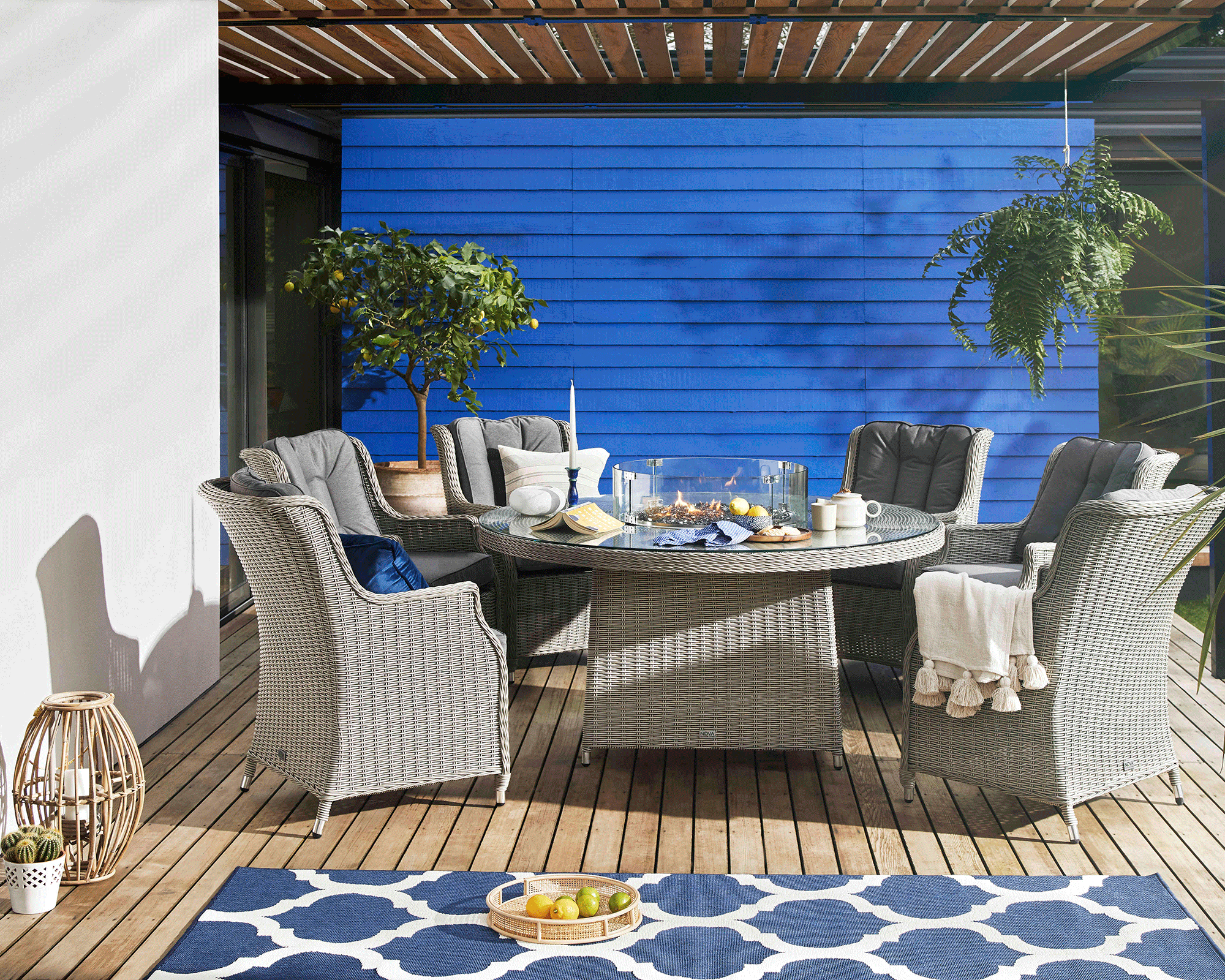 A Med inspired outdoor setting with patio dining chairs and table with central fire pit